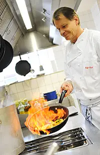 Koch flambiert Gericht in Pfanne