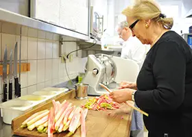 Köchin schneidet Fleisch an Aufschnittmaschine